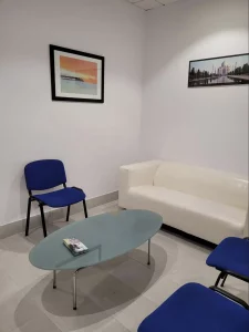 Sala de espera con sofá blanco y sillas azules
