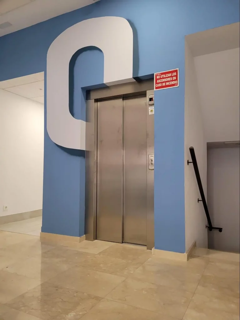 "Ascensor en pasillo con pared azul